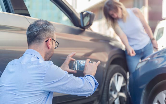 two people reviewing car damage after a car collision